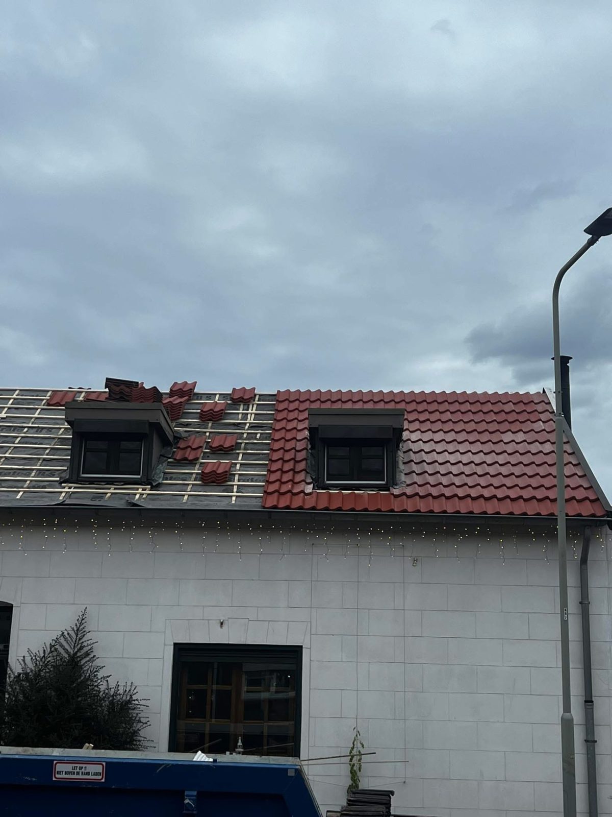 Dakpannen worden vervangen op een woning met dakkapellen